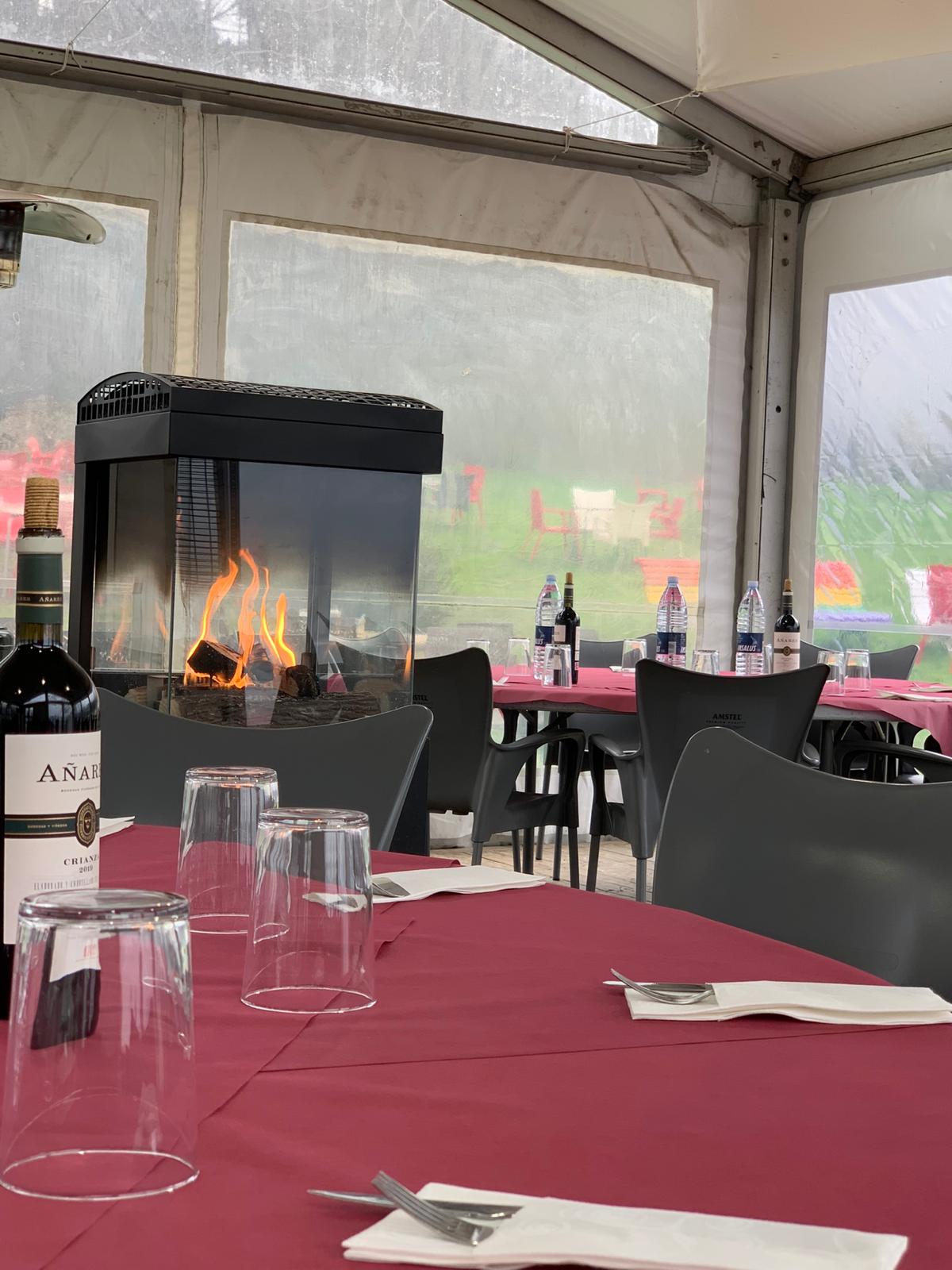 Carpa con chimenea encendida y mesas vestidas para celebraciones